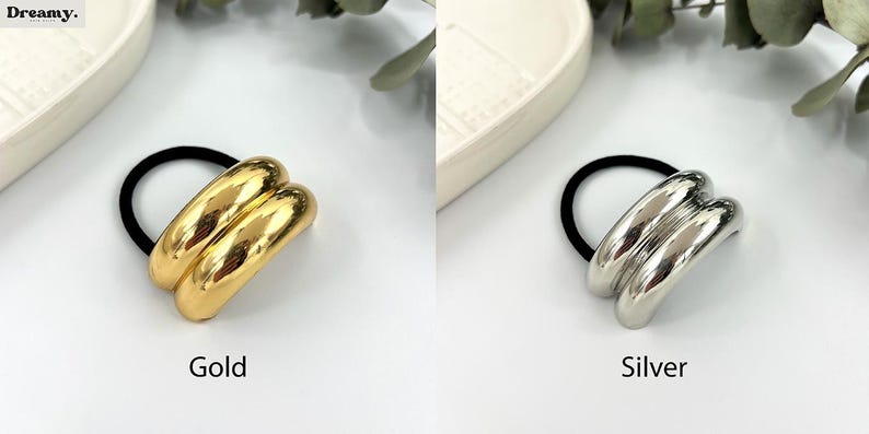 May include: Two hair ties with a double-layered, smooth, rounded metal design. One is gold and the other is silver.