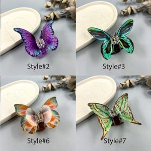 May include: Eight butterfly hair clips in a range of colours, such as green, purple, and yellow. Each clip has a detailed butterfly design with a central jewel. The clips are presented on a neutral background.
