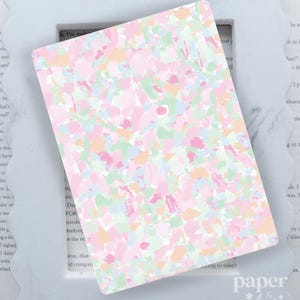 May include: A rectangular card with a pastel abstract design in pink, green, blue, and peach tones. The card is set against a white, scalloped-edge frame. The words "paper & glow" are visible in the bottom right corner.