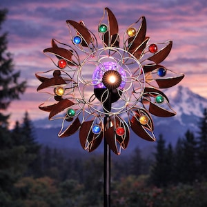 May include: A solar-powered garden wind spinner with a flower design. The metal leaves are brown, and the center features a glowing purple orb and colorful gems. The spinner is mounted on a black pole, set against a scenic mountain backdrop.