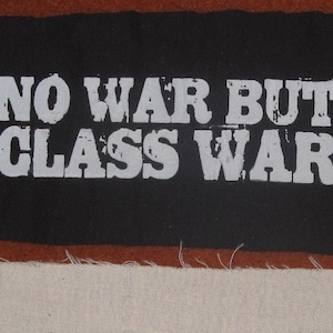 May include: Black fabric patch with white text that reads "NO WAR BUT CLASS WAR".