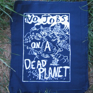 Könnte beinhalten: Ein dunkelblauer Patch mit weißem Text, der "No Jobs On A Dead Planet" lautet. Der Patch zeigt eine Cartoon-Illustration einer Person, die auf einem Planeten arbeitet.