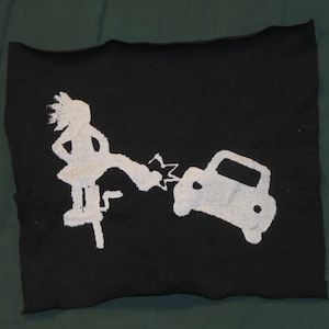 May include: A white silhouette of a person kicking a car on a black fabric background.