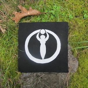 May include: A black fabric patch with a white circle and a stylized female figure holding a circle above her head.
