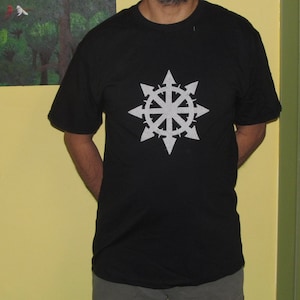 May include: A black t-shirt with a white eight-pointed star design. The star has a circle in the center and points that resemble arrows.
