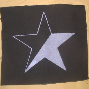 May include: A black fabric patch with a white outline of a star. The star is filled in with a light blue colour.