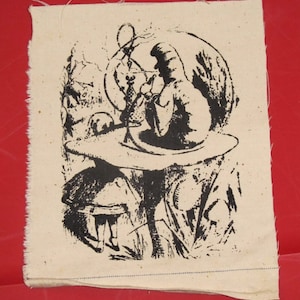 May include: Black and white illustration of a scene from Alice in Wonderland. The Mad Hatter sits on a giant mushroom, smoking a hookah, while Alice stands nearby. The image is printed on a beige fabric.