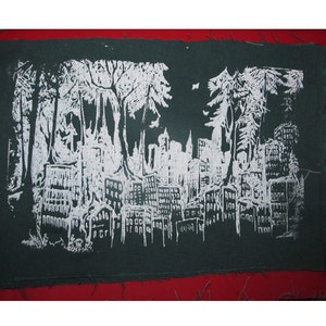 Könnte beinhalten: Ein dunkelgrüner Stoff-Patch mit einem weißen Design einer Stadtlandschaft mit Bäumen im Vordergrund. Die Bäume sind stilisiert und die Gebäude sind einfache Rechtecke.