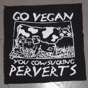 Könnte beinhalten: Schwarz-weiß-Patch mit dem Text "Go Vegan You Cowsucking Perverts" und einer Zeichnung einer Kuh und zweier Personen.