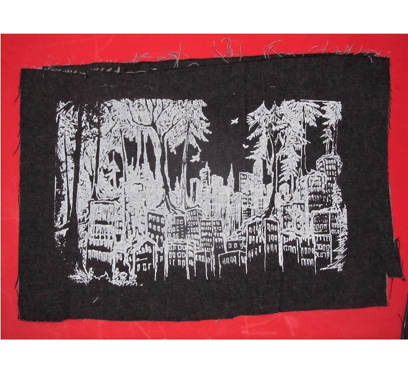 May include: Black and white embroidered patch depicting a cityscape with trees in the foreground. The city skyline is outlined in white against a black background.