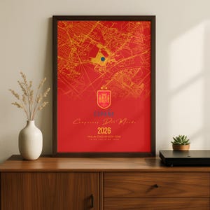 May include: A red poster featuring a yellow street map with a dark blue dot, the Spanish national crest with two stars, and the text ESPAÑA, Campeones Del Mondo, 2026, MetLife STADIUM NEW YORK, and 19 DE JULIO DE 2026 in yellow and blue.