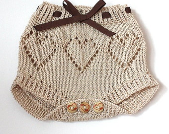 May include: Beige knitted baby bloomers with a brown ribbon bow and heart-shaped buttons.