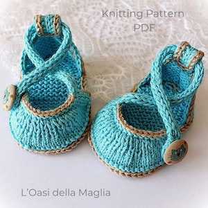 May include: A pair of knitted baby shoes in a light blue color with a brown trim. The shoes have a strap that goes around the ankle and a button closure. The text "Knitting Pattern PDF" is visible.