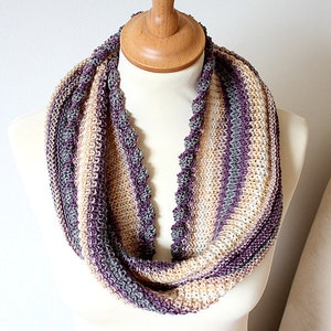 May include: A knitted infinity scarf with a textured pattern in shades of purple, gray, and beige.