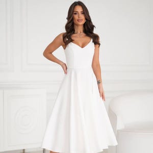 White strappy midi cocktail dress with fitted bodice and flared sun skirt perfect for parties weddings or elegant special occasions