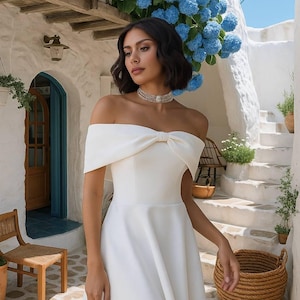 Vestido de noiva elegante branco com ombros à mostra e detalhe de laço