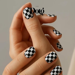 May include: Close-up of a hand with manicured nails. The nails are painted with a black and white checkerboard pattern. The image also includes the text "Dotg Studio Est. 2025".