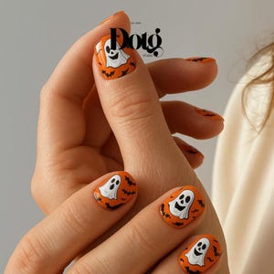 May include: Orange Halloween-themed nail art featuring white ghost designs and black bat accents. The nails are painted with a glossy finish, showcasing a festive and playful design. The image also includes the text "Dotg Studio".