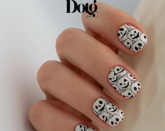 May include: Close-up of a hand with manicured nails. Each nail is painted white and features a repeating black jack-o'-lantern face design. The image includes the text "Dotg Studio" at the top.