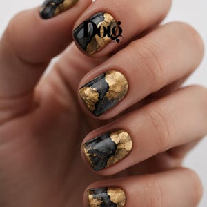 May include: Fingernails featuring a glossy black base coat with intricate, textured gold leaf accents applied in organic, fan-like patterns. The design includes the black text 'Dolg' printed clearly on the middle fingernail surface.