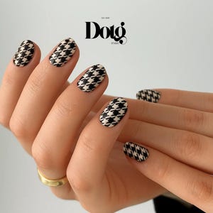 May include: Close-up of manicured nails with a black and white houndstooth pattern. The nails are oval-shaped and have a glossy finish. The image also features the "Dotg Studio" logo.