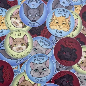 May include: A collection of round stickers featuring stylized cat illustrations with various expressions and phrases. The stickers are in shades of blue, red, green, and brown, with text like "So do I" and "The horrors persist, yet."