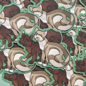 May include: A collection of cat stickers with a green border. The stickers feature cartoon cats in various poses, with colors including brown, tan, and white. The cats have expressive faces and are set against a green background.
