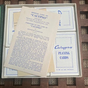 May include: A vintage Calypso playing cards set in its original box. The box is white with blue text and graphics. The set includes a booklet titled "Official Laws of Calypso" and several decks of cards. The cards are a classic game.