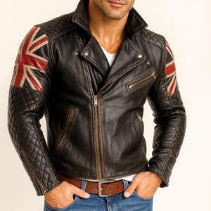 May include: Black leather jacket with a Union Jack flag design on the shoulders. The jacket features a quilted pattern on the shoulders and sleeves, a zipper closure, and a brown belt. The jacket is worn with blue jeans and a white t-shirt.