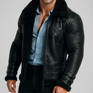 Könnte beinhalten: Schwarze Lederjacke mit Shearling-Kragen und -Futter. Die Jacke hat gerippte Details an den Ärmeln, einen Reißverschluss und Schnallen an den Manschetten. Getragen über einem hellblauen Hemd.