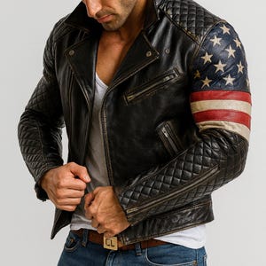 Pu&ograve; includere: Giacca in pelle nera invecchiata con dettagli trapuntati su spalle e maniche. La manica destra presenta un disegno della bandiera americana. La giacca ha un classico stile biker con chiusura a zip e colletto a revers.