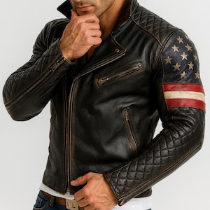 Pu&ograve; includere: Giacca in pelle nera invecchiata con design trapuntato su maniche e spalle. La manica sinistra presenta un motivo a bandiera americana con stelle dorate e strisce rosse e bianche. Chiusura con zip e tasche multiple.
