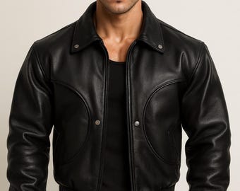 May include: A black leather jacket with a collared neckline and two silver button closures. The jacket has a bomber-style fit with a ribbed hem and cuffs. The jacket has a classic, timeless design.