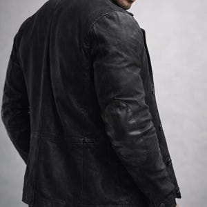 May include: A black leather jacket with a classic design. The jacket features a notched collar, button closure, and elbow patches. The leather has a distressed appearance, giving it a vintage look. The jacket is a stylish outerwear option.