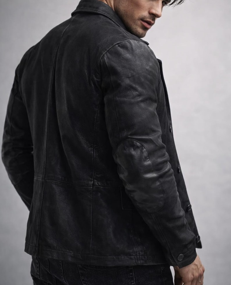 May include: A black leather jacket with a classic design. The jacket features a notched collar, button closure, and elbow patches. The leather has a distressed appearance, giving it a vintage look. The jacket is a stylish outerwear option.