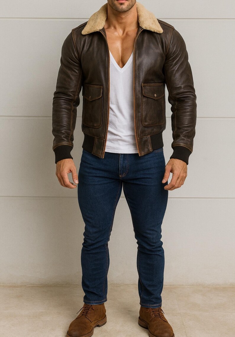 Puede incluir: Chaqueta bomber de cuero marr&oacute;n con cuello de borrego beige, dos bolsillos delanteros y pu&ntilde;os y dobladillo de canal&eacute; negros. La chaqueta se lleva sobre una camiseta blanca con cuello en V y se combina con vaqueros azul oscuro y botas marrones.