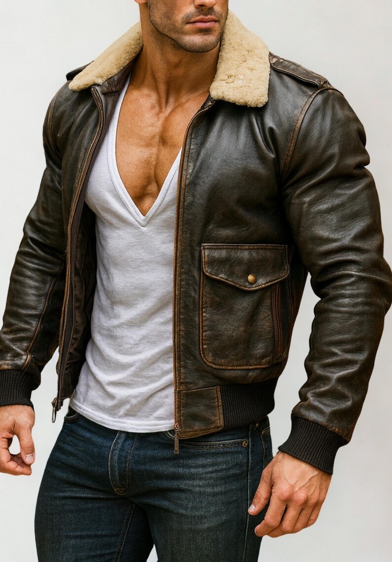 Puede incluir: Chaqueta bomber de cuero marr&oacute;n con cuello de borrego beige, cremallera frontal y dos bolsillos delanteros. La chaqueta tiene pu&ntilde;os y dobladillo de canal&eacute;. El modelo lleva una camiseta blanca con cuello en V y vaqueros azules.