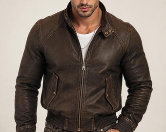 May include: A dark brown leather bomber jacket featuring a stand-up collar with a snap button closure, a central metal zipper, two front pockets with snap flaps, and ribbed knit cuffs and hem, worn over a plain white t-shirt and dark jeans.
