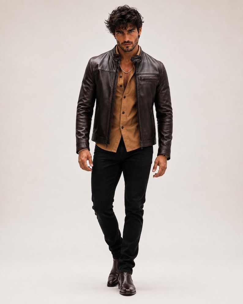 May include: A dark brown leather jacket with a stand-up collar and zippered chest pocket, worn over a tan button-down shirt and black trousers. The outfit is completed with dark brown leather boots, creating a layered look with neutral tones.