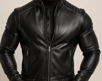 May include: Black leather jacket with a high collar and a zipper closure. The jacket features quilted shoulder detailing and a belt at the waist. The jacket has two zippered pockets and a silver watch.