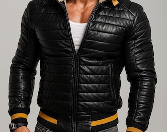 Puede incluir: Chaqueta de cuero negro acolchada con cuello de borrego color crema y detalles amarillos en los puños y la cintura. La chaqueta tiene cremallera y un estilo bomber clásico.