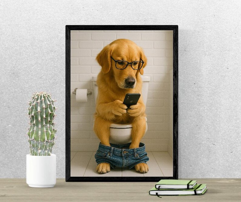 May include: A framed print featuring a golden retriever wearing glasses and denim shorts, sitting on a toilet while looking at a smartphone. The background includes a white tiled wall and a roll of toilet paper.