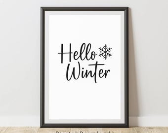 May include: A framed print featuring the words "Hello Winter" in black script, with a snowflake graphic. The text is centered on a white background, within a black frame. The words "Digital Download" are at the bottom.
