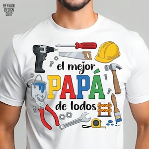 May include: White t-shirt with a colorful graphic design featuring tools and the text "el mejor PAPA de todos". The design includes a drill, saw, hammer, and other construction tools. The shirt is a great gift for Father's Day.