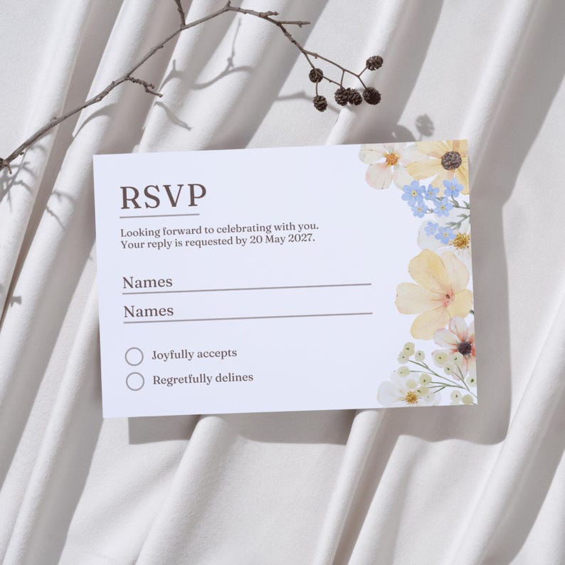 May include: White RSVP card with floral accents in yellow, blue, and white. The card includes prompts for names and acceptance or regretful decline. Text reads "RSVP" and "Looking forward to celebrating with you."