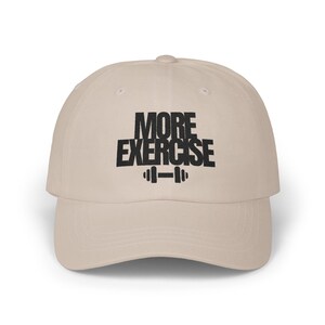 May include: A beige baseball cap with the words "MORE EXERCISE" in bold black letters, along with a barbell graphic. The cap has a curved brim and a classic, casual style.