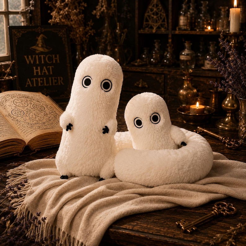 May include: Two white plush figures with soft, fuzzy textures, large circular black and white eyes, and small black hands and feet. One figure stands upright while the other is attached to a long, coiled, plush tail resting on a beige fabric.