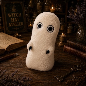 May include: A plush, off-white, fuzzy ghost-shaped figure with two large, circular black embroidered eyes and small, black, three-fingered hands. The soft, textured creature stands upright, featuring a rounded top and a cylindrical body shape.