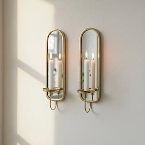 Brass wall candle holders with arched mirrors, displayed with a lit pillar candle and two lit taper candles