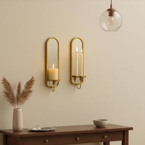 Brass wall candle holders with arched mirrors, displayed with a lit pillar candle and two lit taper candles